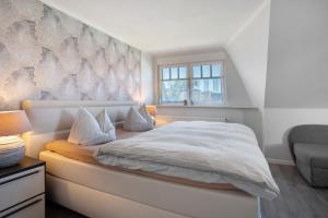 a bedroom with a white bed with a wall at Haus Segelboot Hirtenweg 3c in Zingst