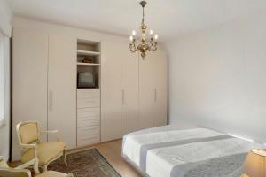 a white bedroom with a bed and a chandelier at Santa Lucia in Imperia