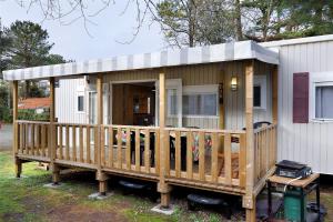 a small house with a porch and a deck at Mobile Home du Bois Dormant in Saint-Jean-de-Monts