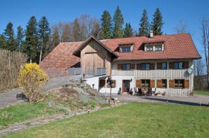 a large wooden house with a red roof at Landhaus Moos in Argenbühl