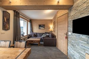 a living room with a couch and a tv on a wall at Appartement au centre de megève in Megève