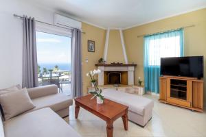 a living room with a couch and a tv at Apartment with Sea view B in Tsoukalades