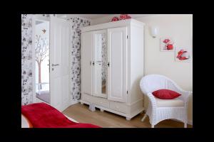 a room with a white cabinet and a chair at Ferienhaus Nanny Und Helene in Uphusum