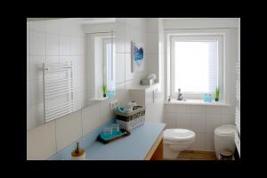 a white bathroom with a toilet and a window at Ferienhaus Nanny Und Helene in Uphusum +20 photos