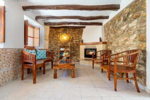 a living room with wooden chairs and a stone wall at La Casa Gran Clariana in Gornal