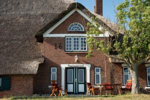 a house with a thatched roof with a table in front at Knutzenswarft - Strandläufer in Westerhever