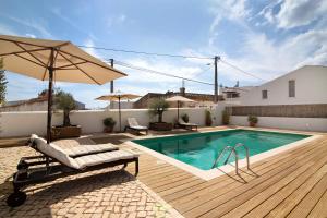 a swimming pool with a chair and an umbrella at Casa de Benafim 1 in Benafim