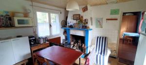 a small kitchen with a table and a fireplace at Petite maison rustique et atypique in Hourtin