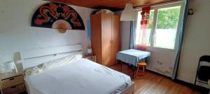 a bedroom with a bed and a desk and a window at Petite maison rustique et atypique in Hourtin