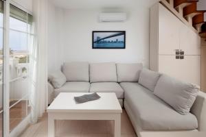 a white living room with a couch and a table at Ático el morche in El Morche