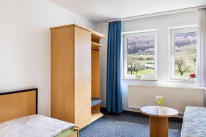 a bedroom with a bed and a table and two windows at Gasthaus, Hotel am Dreienberg in Friedewald