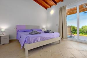 a bedroom with a purple bed and a balcony at Stazzu Gallurese in Olbia