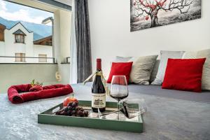 a bottle of wine and grapes on a tray on a bed at Apartment il cuore rosso in Naturno