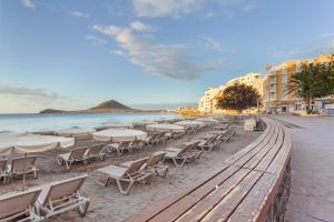 a beach with chairs and tables and the ocean at Medano House in El Médano