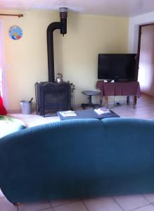 a living room with a blue couch and a tv at Gîte À La Campagne in Bourdeaux
