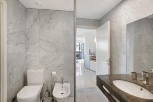 a white bathroom with a toilet and a sink at Apartamento Forum View in Funchal +12 photos