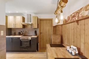 a kitchen with wooden cabinets and a black oven at Ferienwohnung Dorlar in Schmallenberg +26 photos