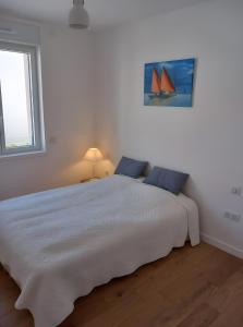 a bedroom with a large white bed with blue pillows at Résidence Oscar Wilde entrée A in Neufchâtel-Hardelot