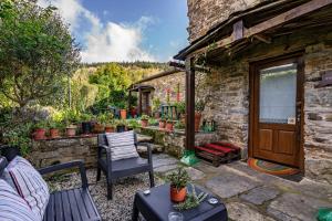 a stone house with a patio with chairs and a door at Teixo in Vega de Logares