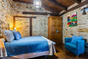 a bedroom with a blue bed and a blue chair at Teixo in Vega de Logares