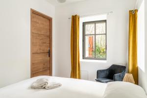a bedroom with a bed and a chair and a window at L'écrin De La Sèvre in Cugand