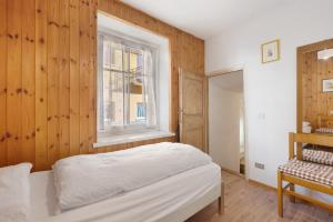 a bedroom with a bed and a window at Casa Mariotta in Castello di Fiemme