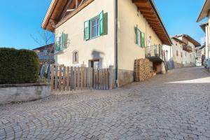 a building with a gate on a cobblestone street at Casa Mariotta in Castello di Fiemme