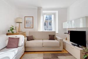 a living room with a white couch and a tv at Casa Mariotta in Castello di Fiemme