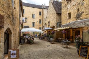 an alley with tables and chairs and umbrellas at Maison de vacances proche de Sarlat in Carsac-Aillac