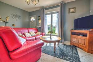 a living room with a red couch and a television at Maison de vacances proche de Sarlat in Carsac-Aillac