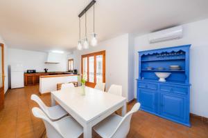 a dining room with a white table and blue cabinet at Es Port in Cala Ratjada