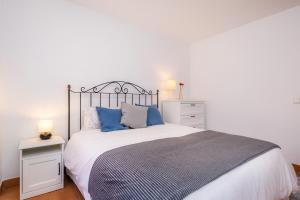 a bedroom with a large bed with blue pillows at Es Port in Cala Ratjada