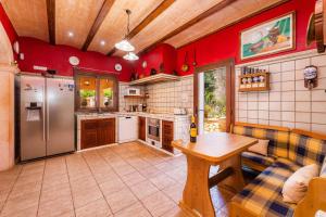 a large kitchen with red walls and a wooden ceiling at Casa Toni in Portocolom