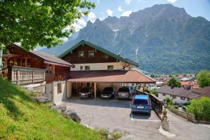 a building with cars parked in a parking lot with mountains at Ferienwohnung Lapislazuli in Mittenwald