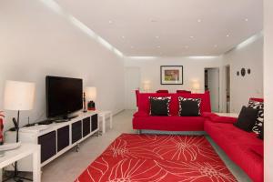 a living room with a red couch and a flat screen tv at Large apartment in Vale do Lobo in Almancil