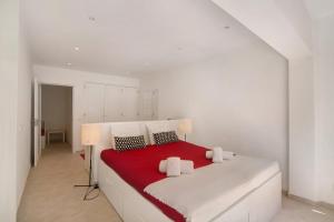 a white bedroom with a red and white bed at Large apartment in Vale do Lobo in Almancil