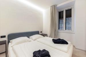 a white bedroom with a bed and a window at App 206 Palazzo Cavour in Bolzano