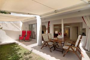 a patio with red chairs and a wooden table at Large apartment in Vale do Lobo in Almancil