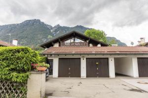 a house with two garage doors with mountains in the background at Ferienwohnung Lilly in Garmisch