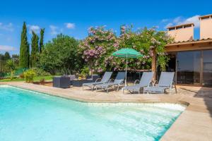 a swimming pool with lounge chairs and an umbrella at Ses Serres in Santanyi
