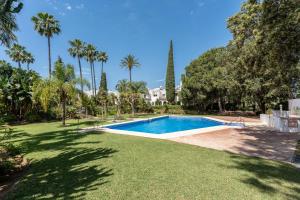 a swimming pool in a yard with palm trees at Casa Karma in Mijas