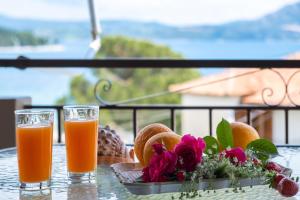 two glasses of orange juice and flowers on a table at Nikoleta Apartment 2 in Nikiana