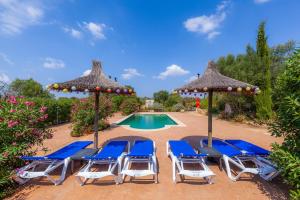 a group of chairs and umbrellas next to a pool at Acuario-Géminis in Llucmajor