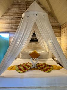 a bedroom with a bed with white drapes at Danys House at Tiki Bar and More in Nusa Lembongan +43 photos
