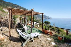 a swing and a chair in a gazebo with the ocean at Villa Lardarina in Corniglia