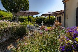 a garden with two umbrellas and flowers at Maison Liz in Castelnaud La Chapelle