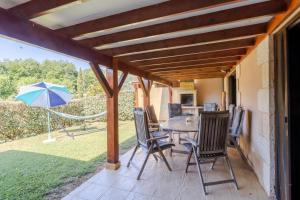 a patio with a table and chairs and an umbrella at Maison Liz in Castelnaud La Chapelle