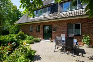 a patio with a table and chairs in front of a house at Ferienhof An Der Wehle Pellworm in Pellworm