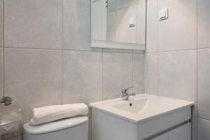 a white bathroom with a sink and a toilet at São Vicente House in São Vicente +15 photos