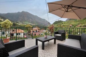 a patio with a table and chairs and an umbrella at São Vicente House in São Vicente